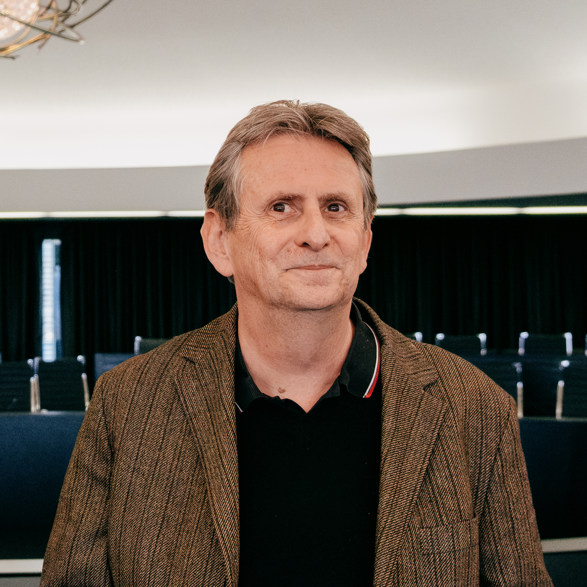 Man in a polo shirt and suit jacket in a meeting room.