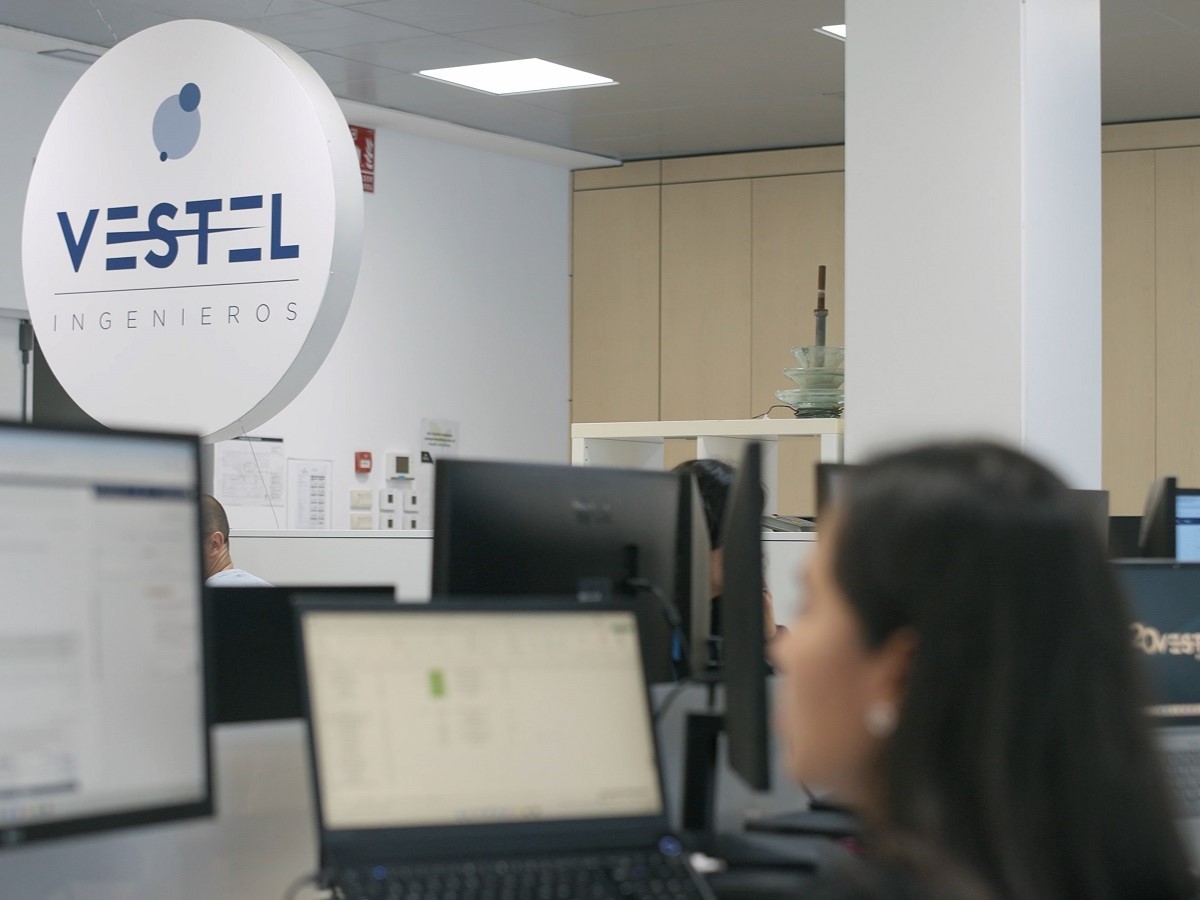 Persona trabajando en las oficinas de Vestel Ingenieros con el logo de fondo