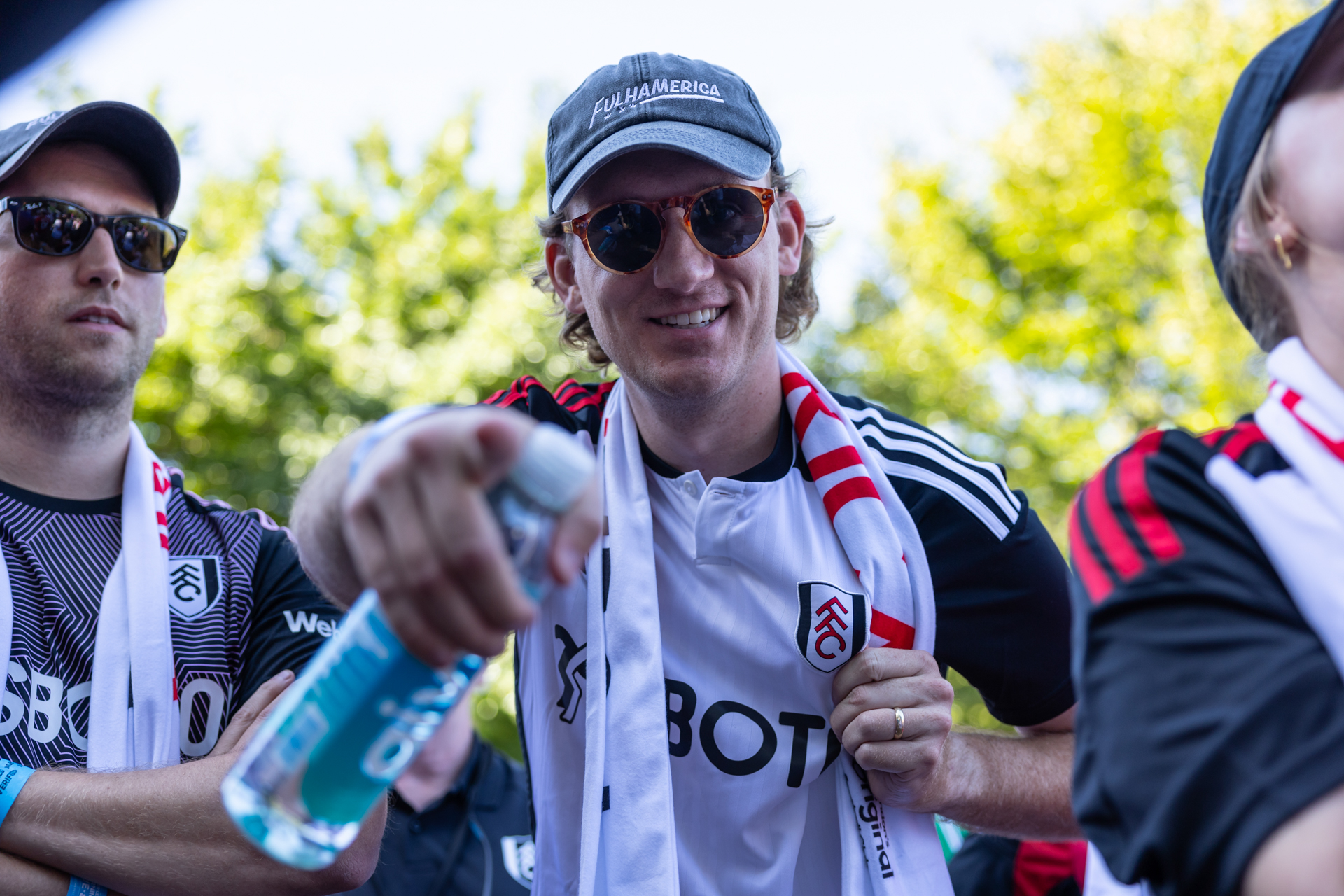 A man wearing a white and black Fulham jersey points at the camera.